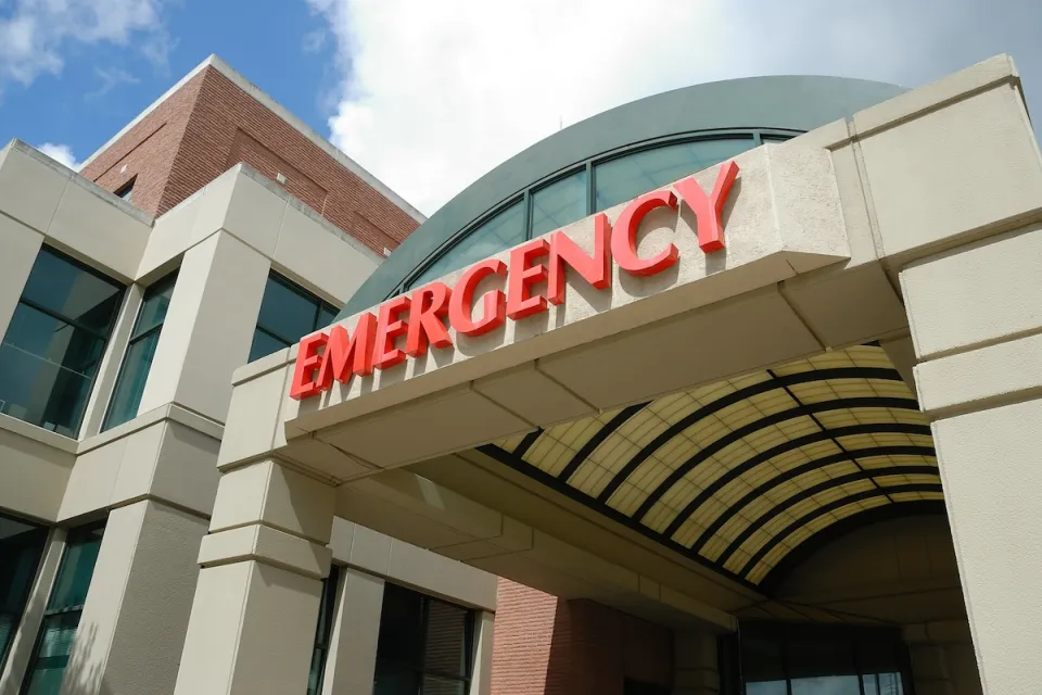 Close-up of red EMERGENCY sign above hospital emergency room entrance.
